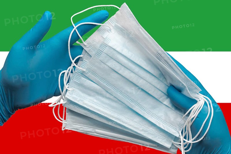Doctor holding face masks in hands medical blue gloves on background national flag Islamic Republic of Iran. Concept coronavirus quarantine, pandemic outbreak, grippe, hygiene. Surgical face bandage