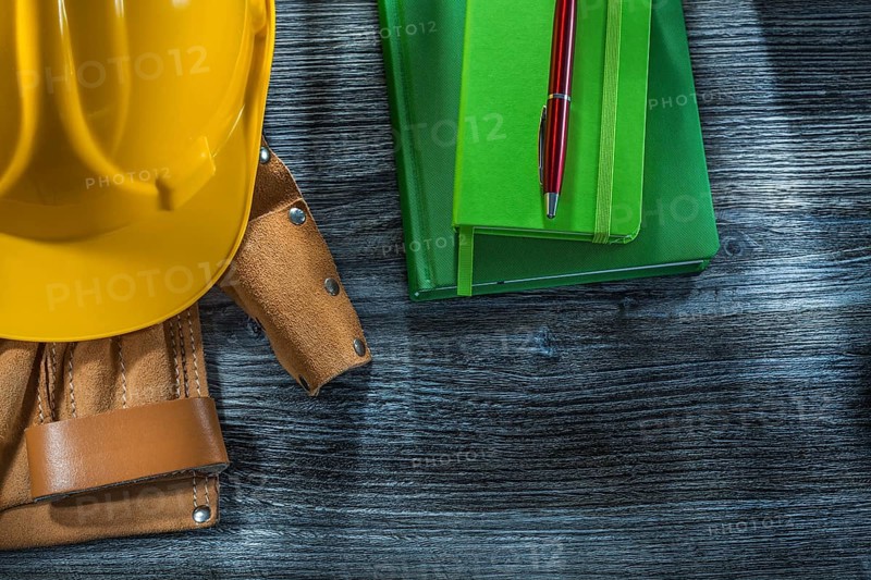Notepads pen building helmet tool belt on wooden board