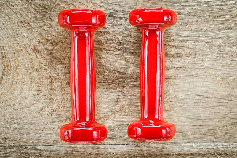 Red dumbbell weights on wooden board fitness concept