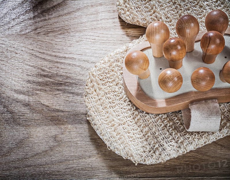 Massager peeling body scrubber on wooden board healthcare concept