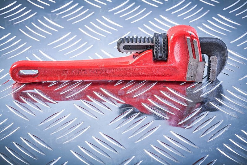 Monkey wrench on channeled metal background construction concept