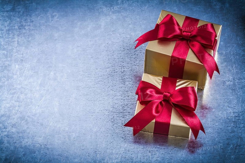 Boxed golden presents with red bow on scratched metallic background