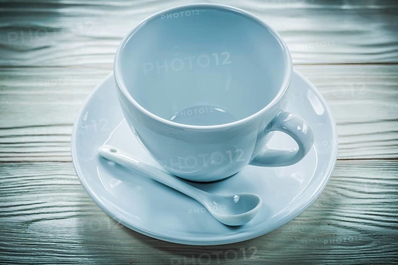 White ceramic cup saucer teaspoon on wooden board