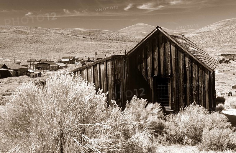 Old wooden shed in Bodie, behind it grassy hills of the prairie. Photo in sepia tone. Old wooden shed in Bodie, behind it graß hills of the prairie. Photo in sepia toning