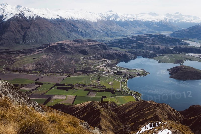 View of a wide valley with a lake, surrounded by fields and mountains, Roys Peak, Wanaka, New Zealand, Oceania