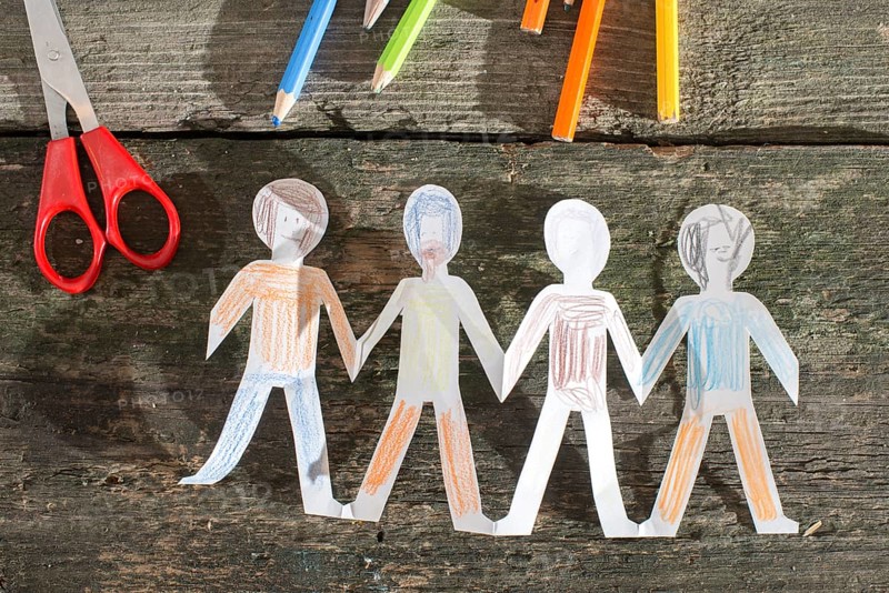 Paper made people figures. Painted white figures on wooden board