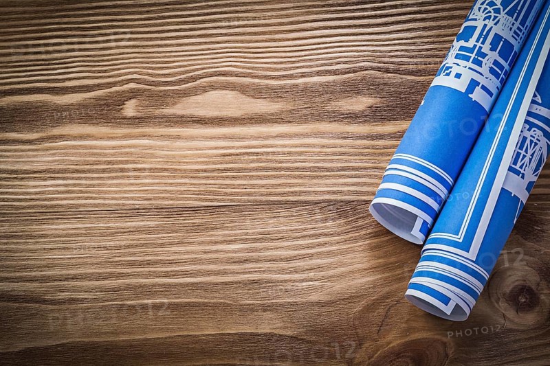 Blue rolled construction plans on wooden board copy space