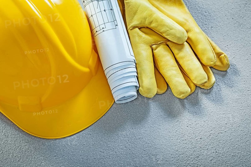 Building helmet protective gloves engineering drawings on concrete surface construction concept