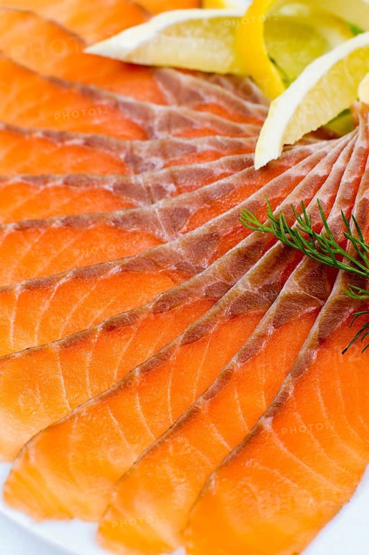 Sliced smoked salmon served with lemon slices