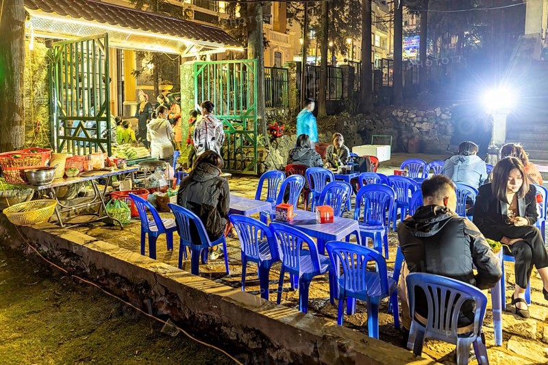 Empty blue chairs and tables under evening lights at a night market, restaurant in the streets of Sa Pa in Vietnam