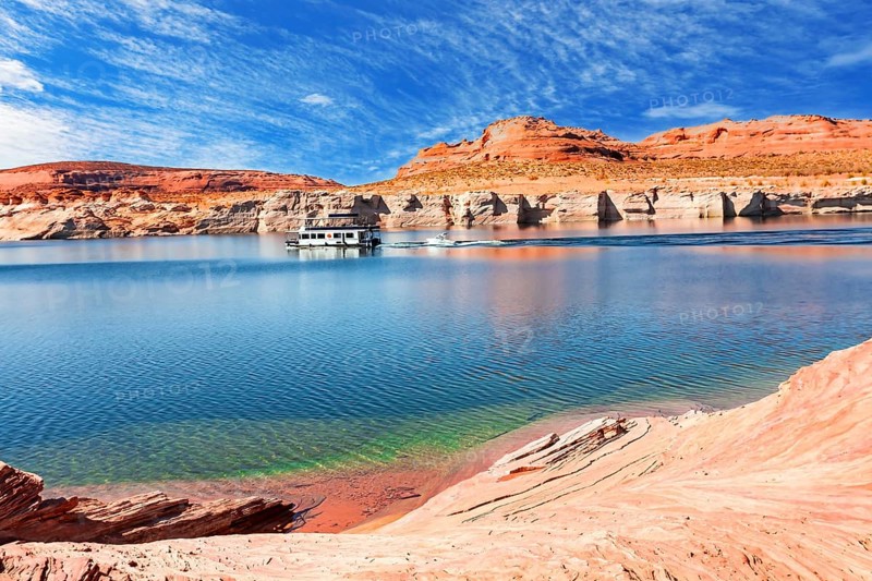 Lake Powell. The coast is cut by narrow canyons. USA. The smooth emerald water of the lake contrasts with the bright red terracotta sandstone shores