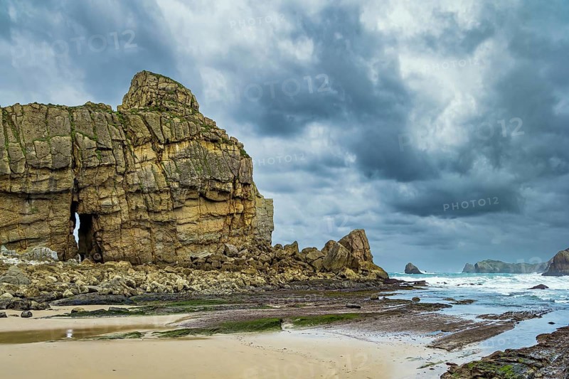 Noon on the beach of Playa di Arnia, Spain. Rocky picturesque ocean coast. Cantabria. Windy stormy day on the Atlantic coast
