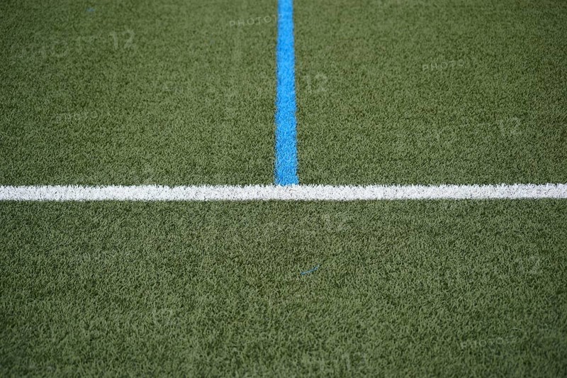 The green turf of a football pitch with the touchline and the centre line