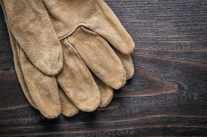 Pair of leather working gloves on vintage wooden board construction concept
