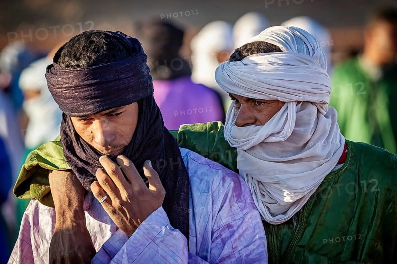 Two men in traditional dress and turbans, one puts his arm around the other, The traditional Tuareg at the Tamanrasset Festival in the Sahara in Algeria