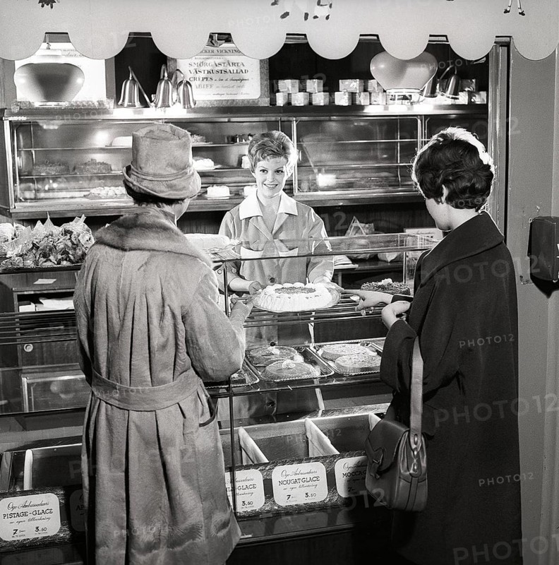 1960s coffee shop. Two women are standing in front of the counter that is full with freshly baked cakes and pastries. Sweden 1960s ref CX80-3