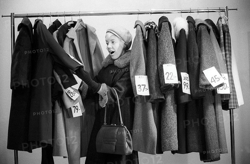 Great discounts of outerwear in the 1960s. A woman stands by a clothes rack, choosing from outerwear and coats marked with price tags with discounted prices. Judging by her face, she appreciates the reduced prices and thinks she's getting real bargains. Sweden January 1963. Ref CV28