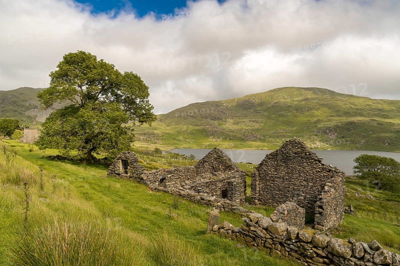 Grey clouds over Llyn Cwmystradllyn with a derelict ruin on the shore, near Penmorfa, Gwynedd, Wales, UK