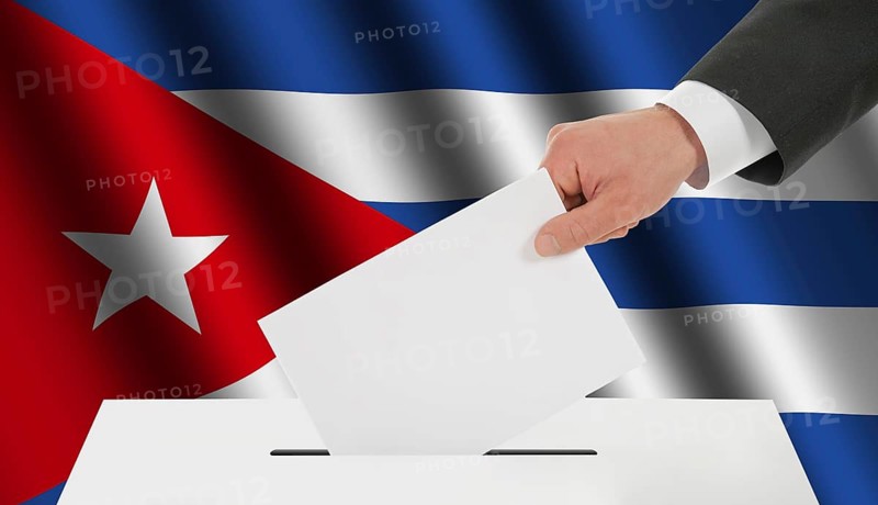 The Cuban flag and the hand with the bulletin about the ballot box