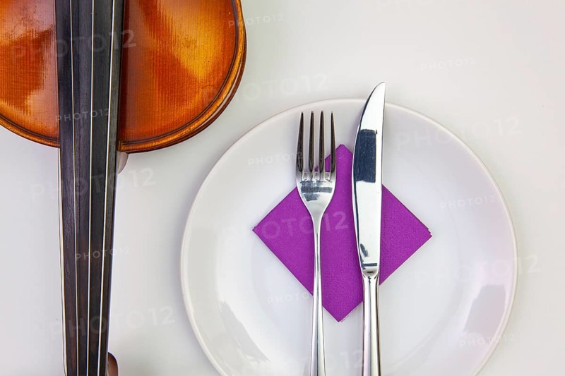 Symphony of taste. White plate and old violin on the white wooden table.Top view. Flat Lay Image