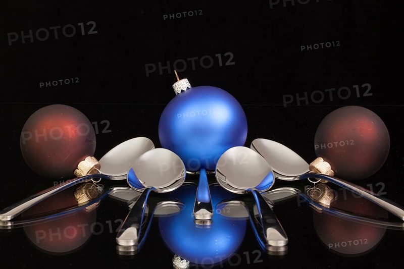 Blue Christmas decoration and five spoons on a black glass desk