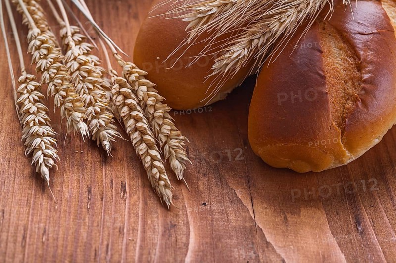 Bread with wheat ears on old wooden board