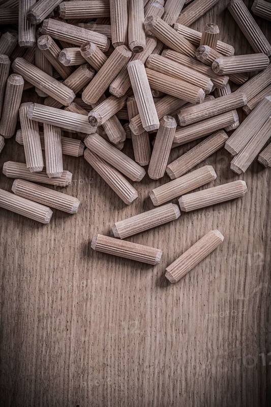 Variety of cylinder wooden dowel pins on wood board construction concept