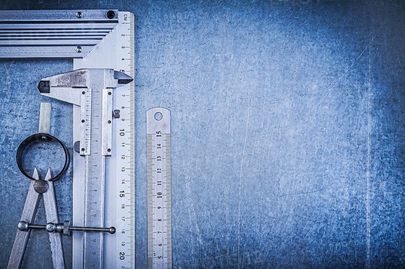 Metal ruler try square slide caliper construction divider on metallic background