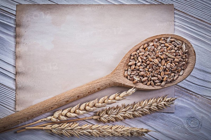 Golden wheat rye ears grain wooden spoon clean vintage paper sheet on wood board top view