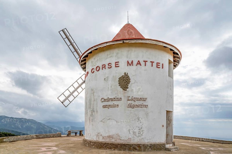 The whitewashed windmill Moulin Mattei with tiled roof and wind vanes at the Col de la Serra of the spirits producer L.N.Mattei is the landmark of Cap Corse, Corsica, France, Europe