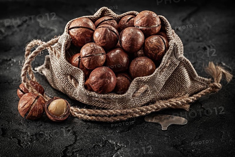 Opened Full Of Macadamia Nuts Burlap Bag On Dark Background