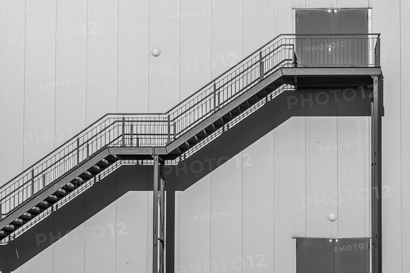 Greyscale shot outdoor stairway to the building in the sun