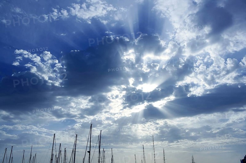 Cloudy sunset beam sky with marina sailboat masts on bottom