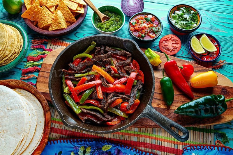 Beef fajitas in a pan with sauces chili and sides Mexican food