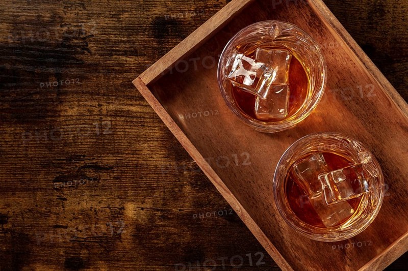 Whiskey in glasses with ice. Bourbon whisky on rocks on a dark rustic wooden background, overhead flat lay shot with copy space, Food photography, Food photography