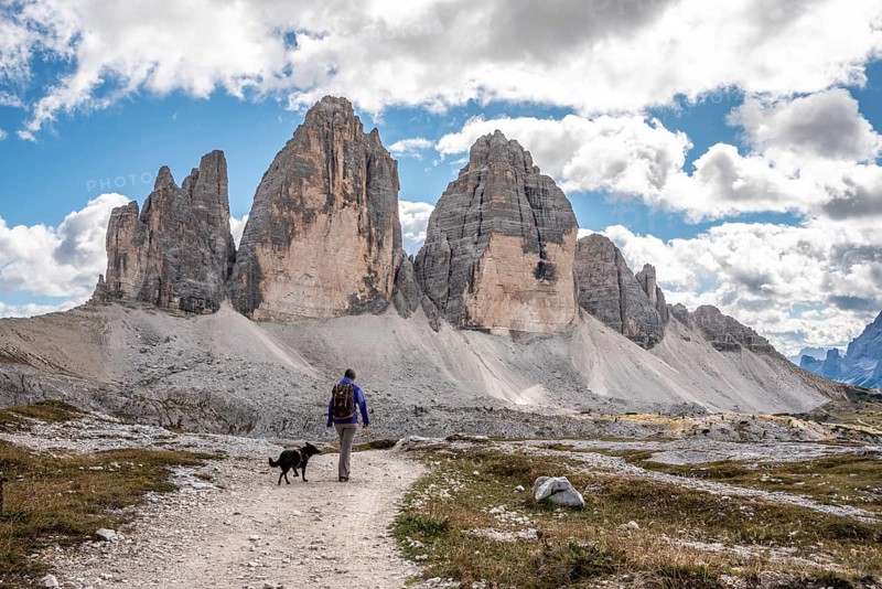A female person hiking lonely with her dog around the Drei Zinnen mountains, the Dolomites in South Tirol