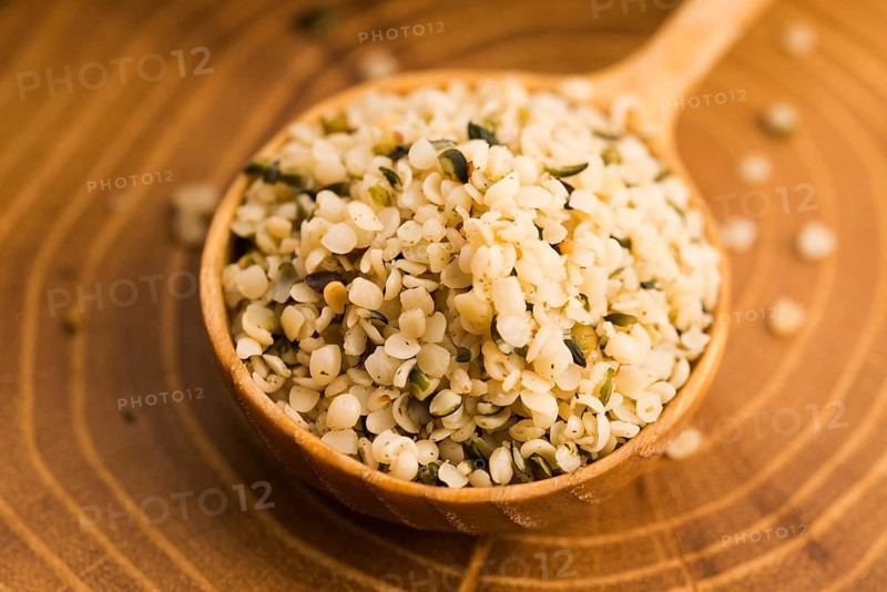 Shelled hemp seeds on wood background