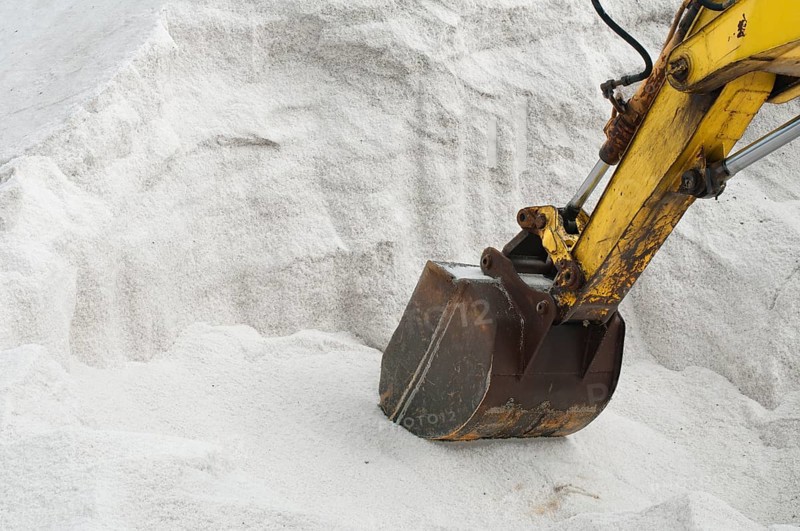 Excavator digging pile white salt