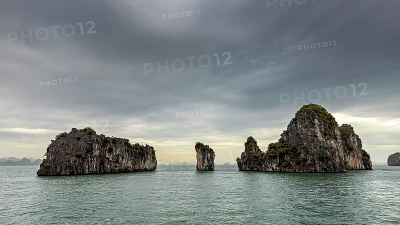 Rocky islands in the calm sea under a grey sky, The landscape and islands of Halong Bay in Vietnam