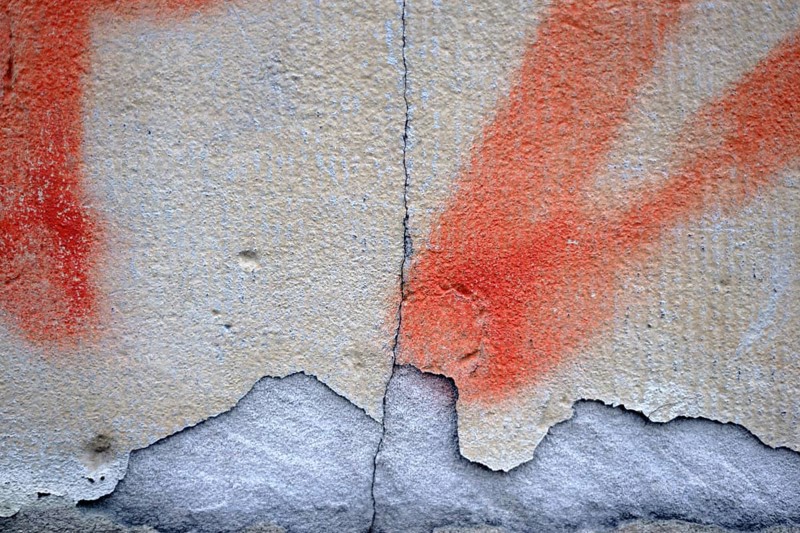 Close-up of a wall with a chipped and painted layer of plaster
