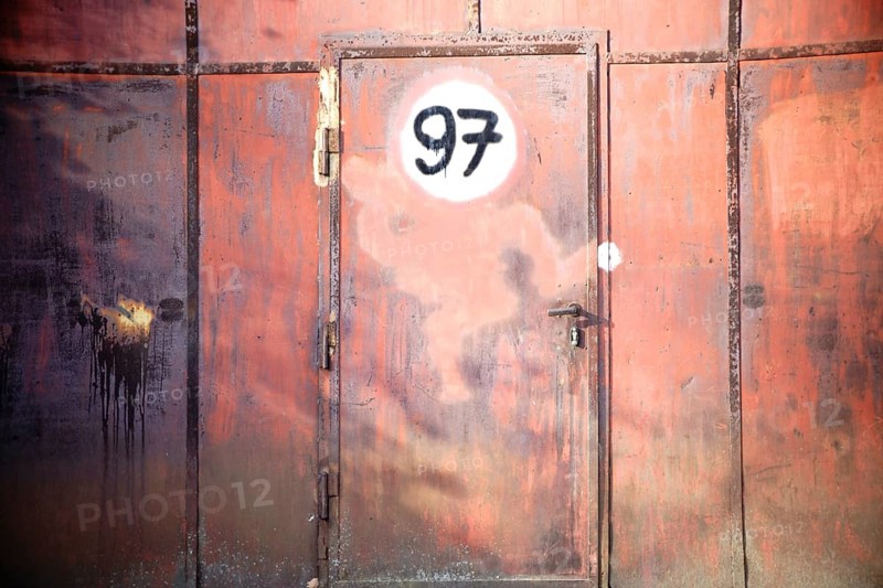 A rusty iron gate with a door and a painted sign