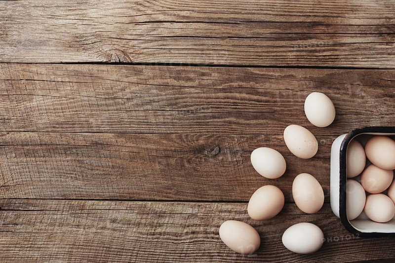 Organic chicken eggs in metal box on wooden background in a row. Organic household concept with eggs from free-range and pasture raised hens
