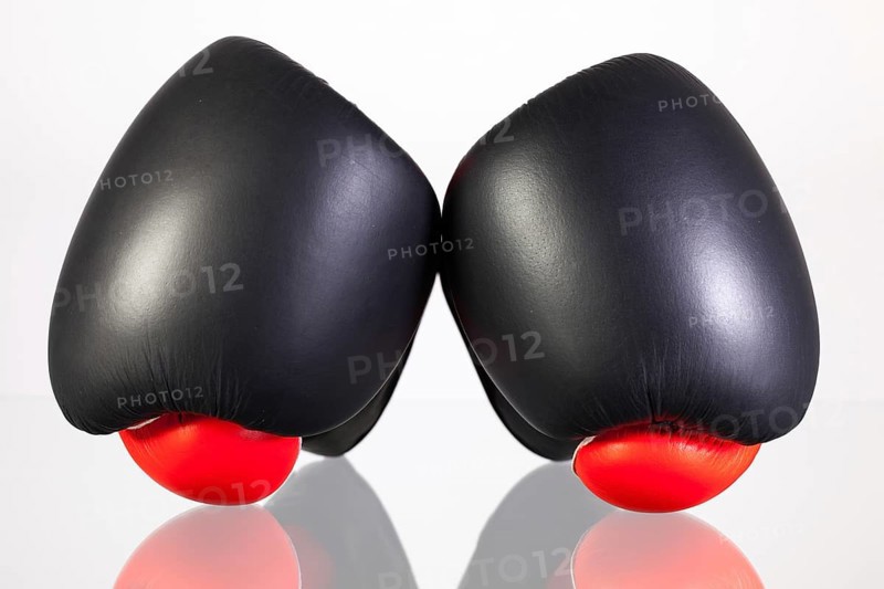 Red and black boxing gloves on a glass table isolated on white background