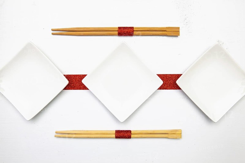 Ceramic bowls and bamboo chopsticks for sushi food with red and white decoration