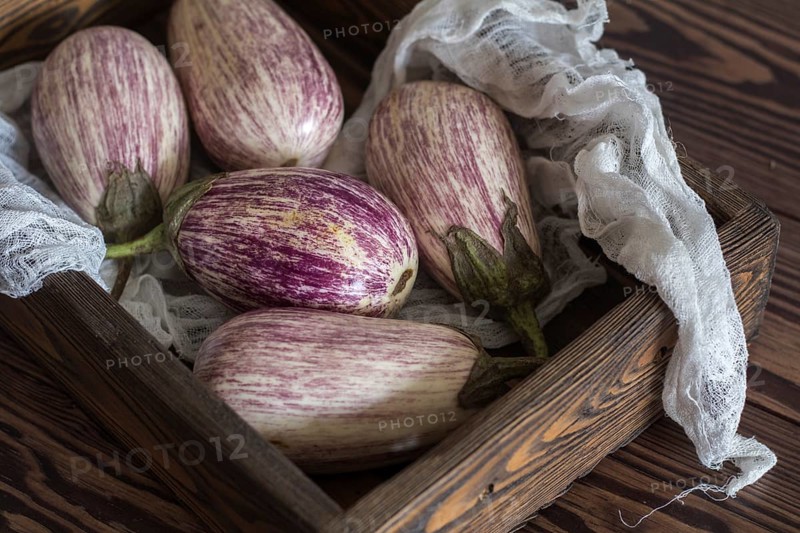 Purple graffiti eggplants in a wooden box in a vintage wooden background in rustic style, selective focus
