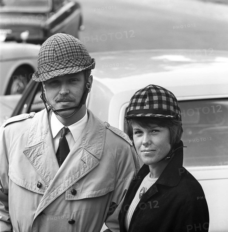 Driving in the 1960s. Car helmets was introduced in Sweden to encrease personal safety when driving cars. The manufacturers of the helmets hoped the sales of them would be boosted by the upcoming change from driving on the left side on the road, to the right. Oddly enough fewer accidents happened then prior the change. Pictured are a young couple wearing their helmets that were made differently for men and women. Sweden 1966 ref CV38-2