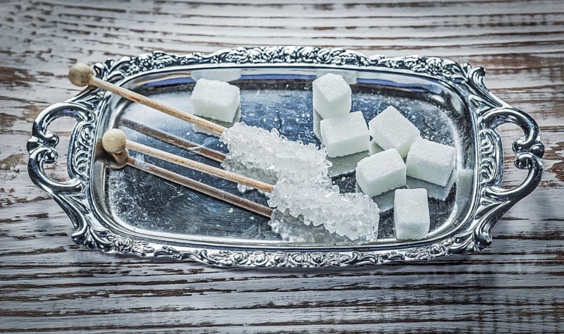 White sugar cubes sticks tray on vintage wooden board