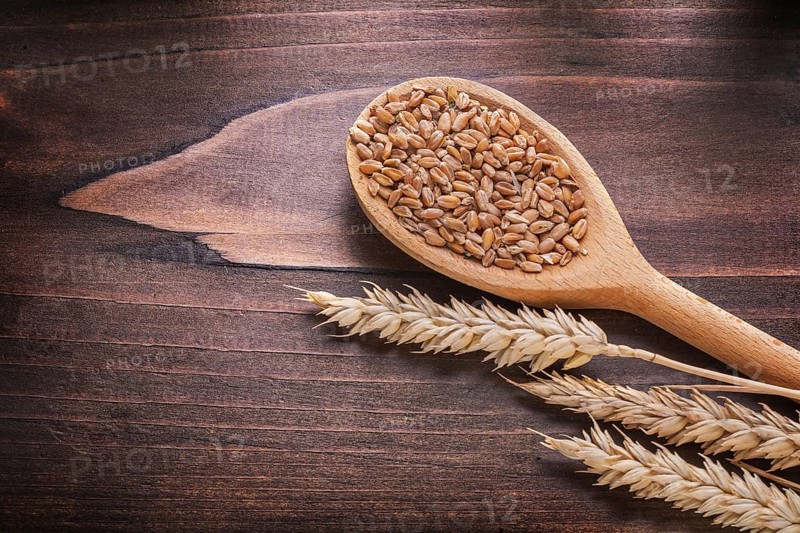 Wooden spoon with corns of wheat and ears on vintage board food and drink concept
