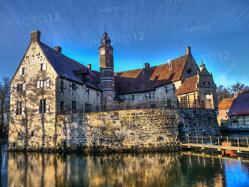 Medieval castle with a moat, shining in the sunlight against a blue sky, Lüdinghausen, münsterland, germany