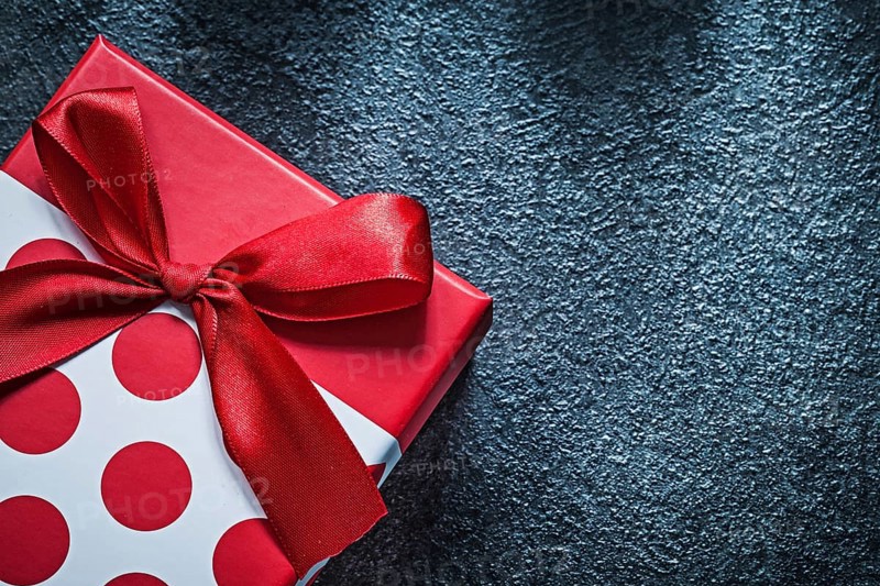 Wrapped gift box with tied bow on black background celebrations concept